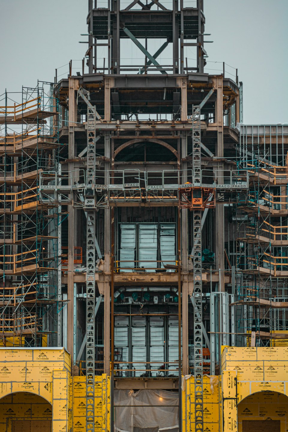 Edificio in costruzione con struttura in acciaio e rivestimento giallo.