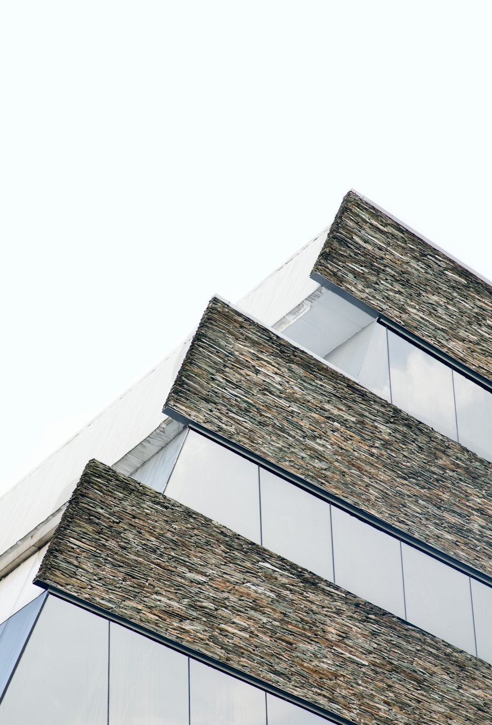 Facciata di un edificio moderno con elementi in pietra, vetro e bianchi.