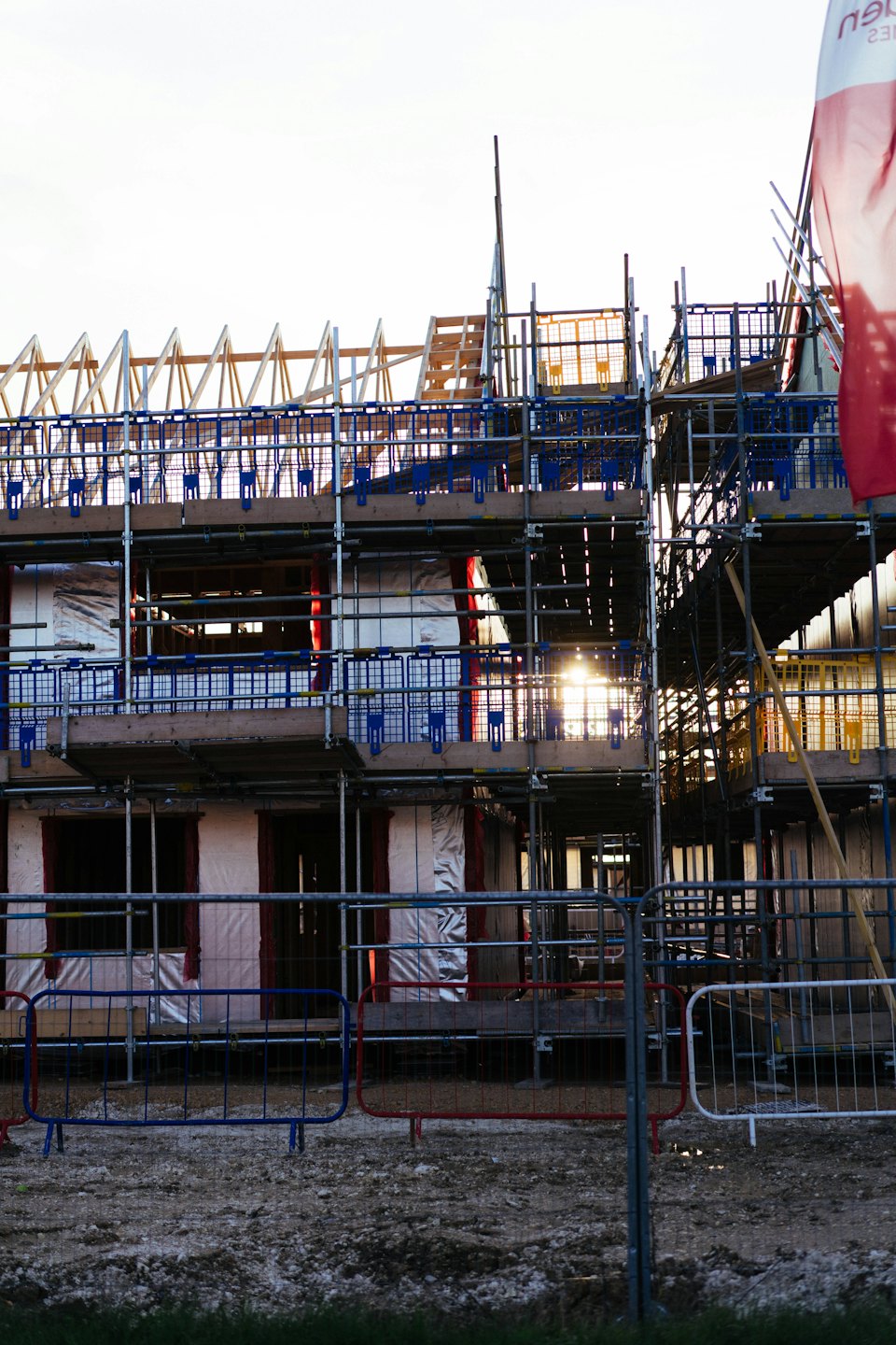 Edificio residenziale in costruzione coperto da ponteggi con rete di sicurezza blu.